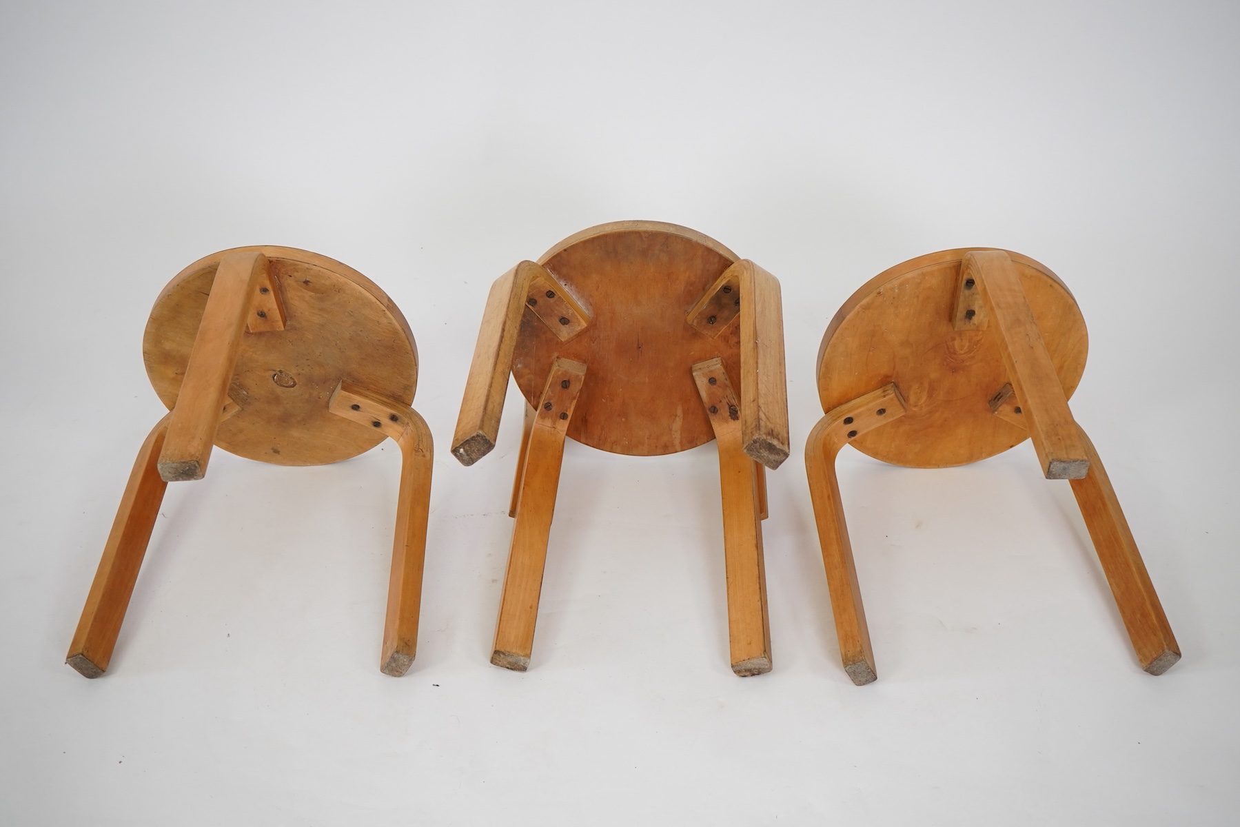 Alvar Aalto (Finnish 1898-1976) for Artek, distributed by Finmar: A pair of 'Model 60' stools and a similar 'K65' stool